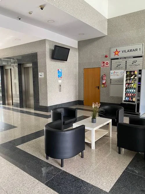 Pantalla, máquinas expendedoras y cartel informativo en el hall de entrada del Edificio Vilamar en Sevilla