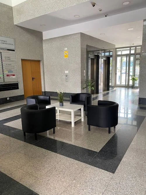 Detalle de sofás individuales y mesa en el hall de entrada del Edificio Vilamar en Sevilla