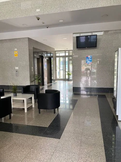 Hall de entrada del Edificio Vilamar en Sevilla con sofás, mesita baja y decoración elegante