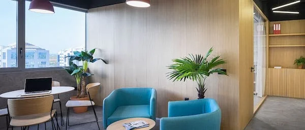 Zona de Descanso con Sofás, Mesita de Café, Mesa con Sillas y Plantas en BySpaces Coworking, Sevilla